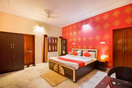 a bedroom with a bed and a red wall at OYO The Nandini's Guest House in Jaipur