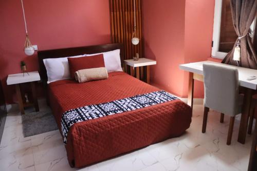 a bedroom with a red bed and a desk at Casa 2 in Namibe