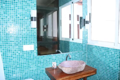 Baño de azulejos azules con lavabo y espejo en Casa 2, en Namibe