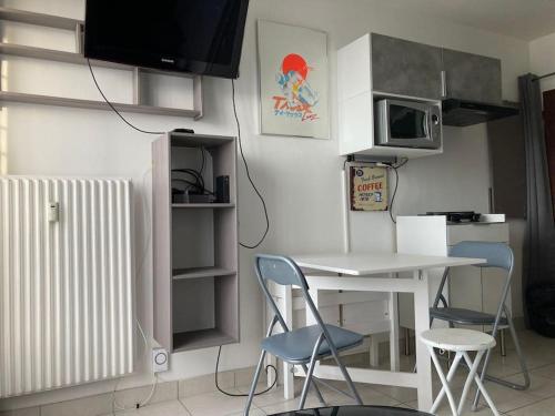 une cuisine avec une table, deux chaises et une table avec un four micro-ondes dans l'établissement Studio Tout équipé Evreux, à Évreux