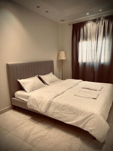 1 dormitorio con 1 cama blanca grande y ventana en اجنحة فندقية 3 Suites en Abalah