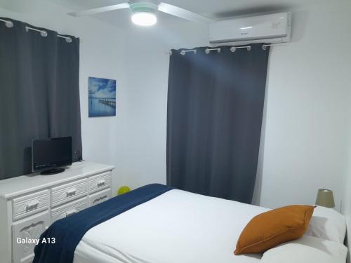 Schlafzimmer mit einem Bett und einer Kommode mit einem TV in der Unterkunft Centric and cozy apartment in Punta Cana