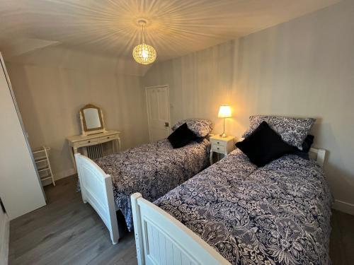 a bedroom with two beds and a mirror and a lamp at Limes Cottage in Cowbridge
