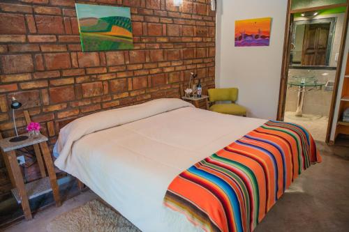 uma cama num quarto com uma parede de tijolos em Posada Boutique El Encuentro Chacras de Coria em Chacras de Coria