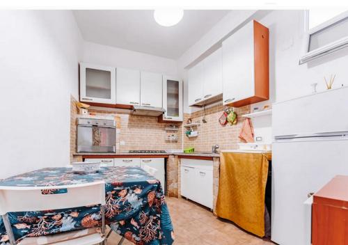 una cucina con mobili bianchi e tavolo di Casa vacanze Cagliari Poetto a Quartu SantʼElena