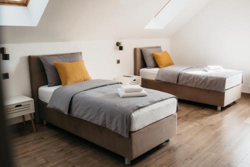 Duas camas num pequeno quarto com pisos em madeira em Pansion Mihića dvori em Babina Greda