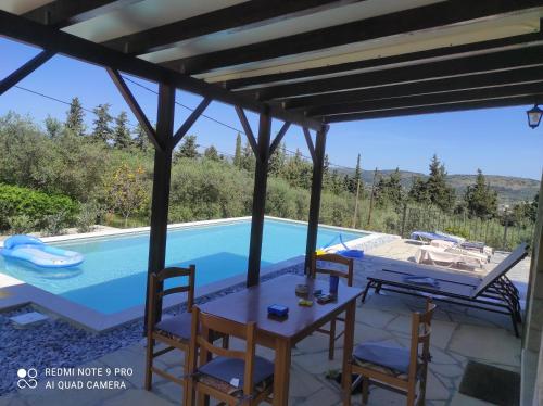 uma villa com uma piscina, uma mesa e cadeiras em VILLA IRIS em Vryses