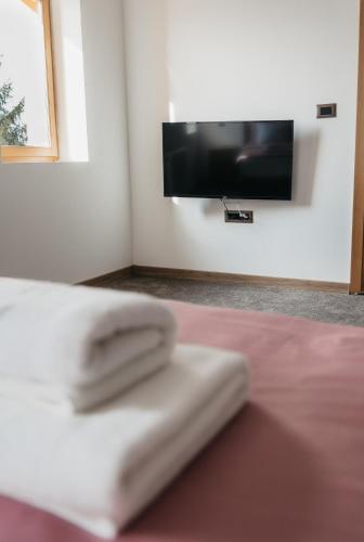 a pair of towels sitting on a bed with a tv on the wall at Pansion Mihića dvori in Babina Greda