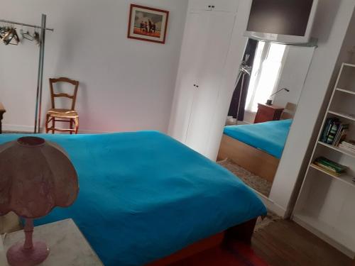 sypialnia z niebieskim łóżkiem i krzesłem w obiekcie Appartement Petroff w Paryżu