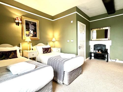 a bedroom with two beds and a fireplace at Colthrop Manor B&B in Thatcham