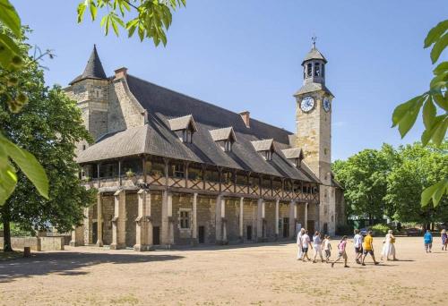 a large building with a clock tower with people walking in front at La villa des jonquilles in Saint-Victor