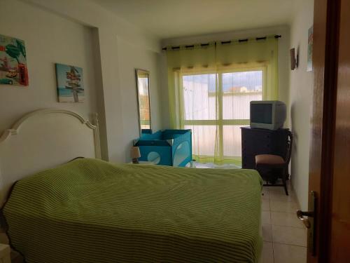 um quarto com uma cama, uma televisão e uma janela em Casa Moderna em Atouguia da Baleia