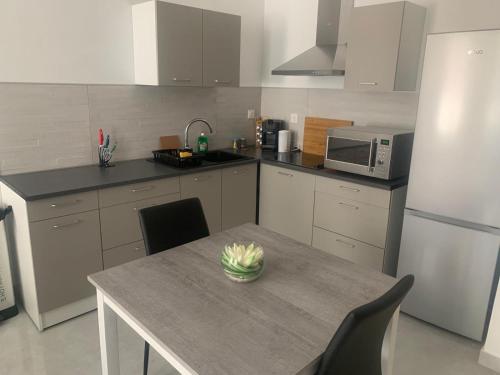a kitchen with a table and a microwave and refrigerator at Chez Émilie et John in Saint-Étienne
