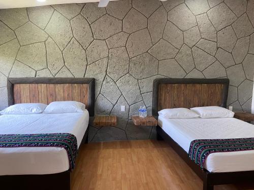 2 Betten in einem Zimmer mit einer Wand in der Unterkunft Tonantzincalli SPA Prehispanico in Chiconcuac