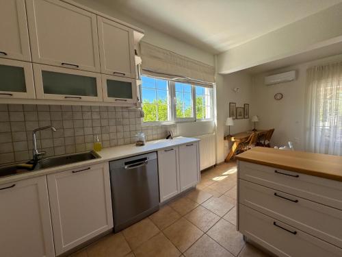 een keuken met witte kasten, een wastafel en een raam bij Primavera Retreat in Chania