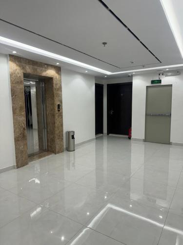 une grande pièce vide avec un sol blanc et une porte dans l'établissement توبال الماسي, à Sīdī Ḩamzah