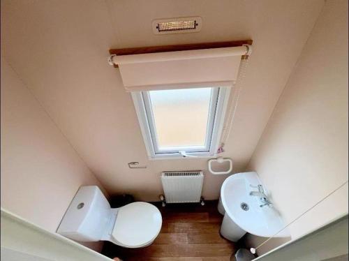 a bathroom with a toilet and a sink and a window at La Casa Greenaway in Jaywick Sands