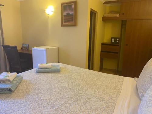 a bedroom with a bed and a desk and a refrigerator at Hostal Solor in San Pedro de Atacama