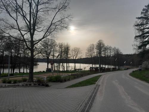 uma estrada vazia ao lado de uma massa de água em Domek Gościnny nad jeziorem Limajno em Olsztyn