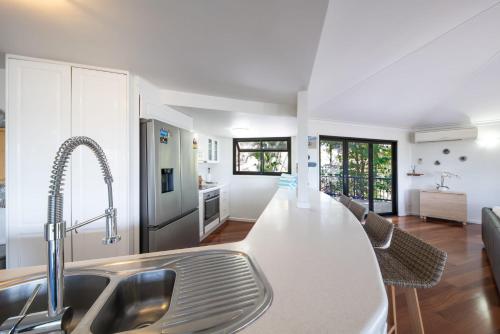 a kitchen with a white counter top and a sink at 'Sail Away' Airlie Beach house with Marina Views in Airlie Beach