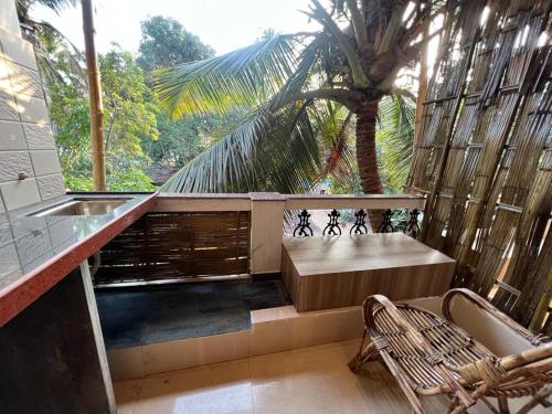 a balcony with a bench and a palm tree at Jeet Hostel & Rooms in Canacona