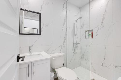 a white bathroom with a toilet and a shower at Le Mile End by M11 - Neat & Spacious 1BDR Unit in Montréal