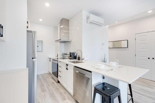 a white kitchen with a sink and a refrigerator at Le Mile End by M11 - Neat & Spacious 1BDR Unit in Montréal
