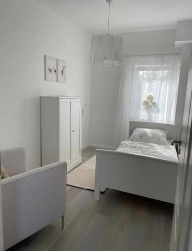 Habitación blanca con cama y ventana en HOME OF VACATION - Landhausstil zum Wohlfühlen - FREE WIFI & NETFLIX, en Adelheidsdorf