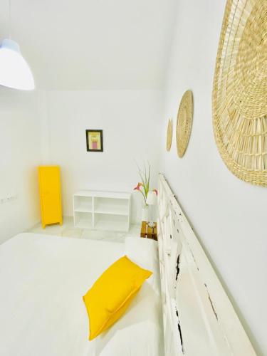 una camera bianca con un cuscino giallo su un letto di SOLEO suite a Jerez de la Frontera
