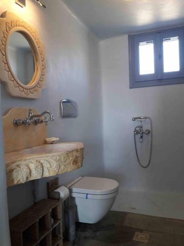 a bathroom with a sink and a toilet and a mirror at Nightsky Tinos Villa w Unrestricted View in Tripótamos