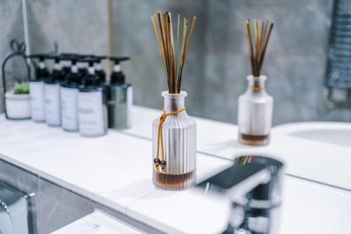 two vases with reeds in them sitting on a bathroom counter at Windmill Suite- Modern 2 bed 2 bath with concierge perfect for leisure, business and contractor stays by Dreamluxe in Birmingham