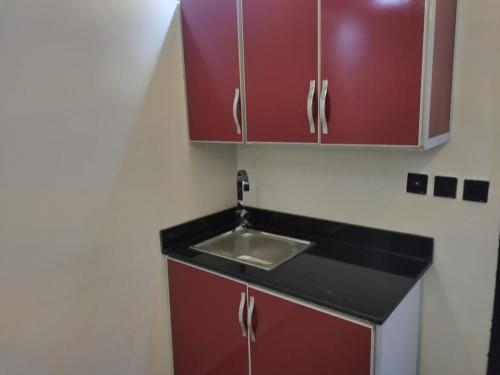 a kitchen with a sink and red cabinets at Jeddah Grand Beach in Jeddah