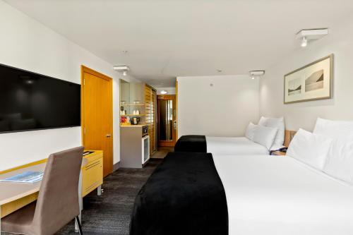 a hotel room with a large bed and a desk at Novotel Queenstown Lakeside in Queenstown
