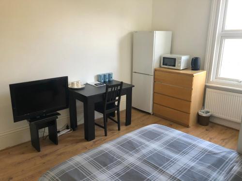 a room with a desk with a television and a refrigerator at London x DM Weekly x Monthly Discounts x W13 in Greenford