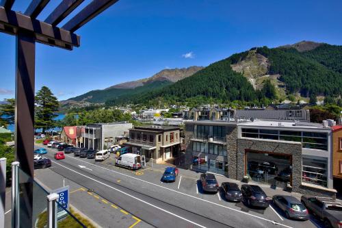 a city with cars parked on a street with mountains at Novotel Queenstown Lakeside in Queenstown