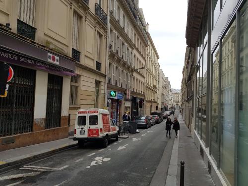 una calle de la ciudad con una pequeña furgoneta aparcada en la calle en Appartement d'architecte au cœur de Paris 9, en París