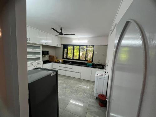a kitchen with white cabinets and a ceiling fan at Luxurious 2Bhk Fully Furnished apartment in Pune