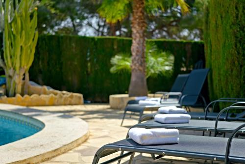 a row of lounge chairs next to a swimming pool at Villa Mariposa in Calpe