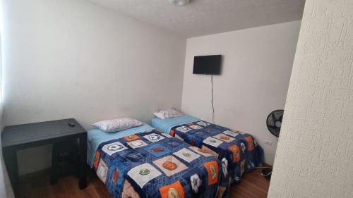 1 dormitorio con 2 camas, escritorio y TV en Bonita casa al norte de Aguascalientes en Jesús María