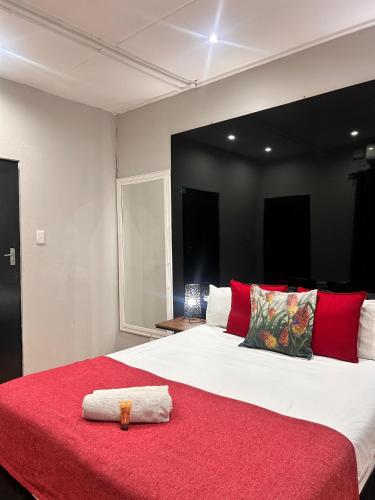 a bedroom with a large bed with a red blanket at Bothabelo Bed and Breakfast in Phalaborwa