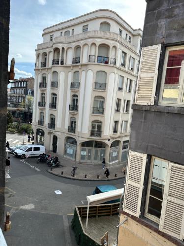 un grande edificio bianco con un parcheggio di fronte di Nid Confort - 2 pas à la place de Jaude a Clermont-Ferrand
