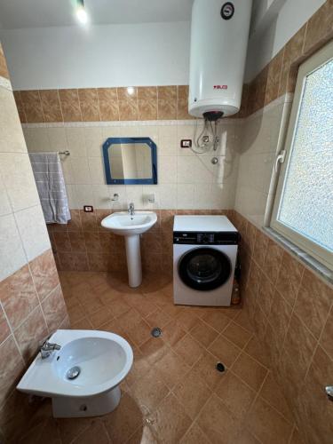 y baño con lavadora y lavamanos. en Himara Apartment, en Himare