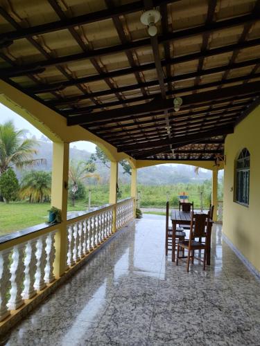 un porche de una casa con mesa y sillas en Casa Amarela Hostel, en Barão de Cocais