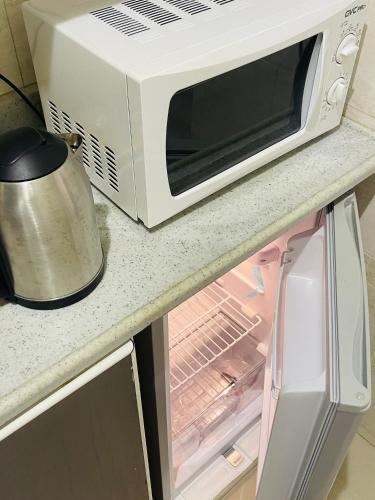 eine Mikrowelle auf einer Theke neben einem Kühlschrank in der Unterkunft ماكس الفندقية ٣١ in Riad