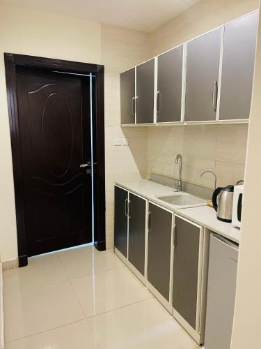 eine Küche mit einer schwarzen Tür und einem Waschbecken in der Unterkunft ماكس الفندقية ٣١ in Riad