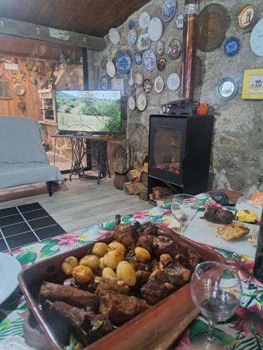 a table with a pan of food and a tv at Casa do Garrano - Gerês in Vilar da Veiga