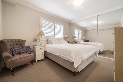 una camera con letto, sedia e specchio di Walk to Coogee Beach Apartment Retreat a Sydney