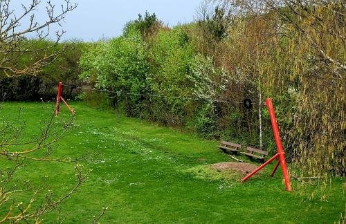 a park with a bench in a grass field at Ferienhaus Grüner Bungalow Kontaktloser CheckIn in Stendell