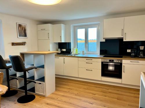 a kitchen with white cabinets and a table and chairs at Gästhaus "Seeblick" in Seekirchen am Wallersee