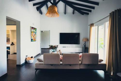 a living room with a couch and a flat screen tv at Villa Mahé, Majestueuse villa avec piscine, F4 à Ducos in Ducos